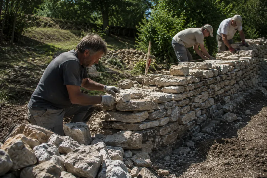Illustration d’ambiance : des artisans montent un mur de pierre sèche.